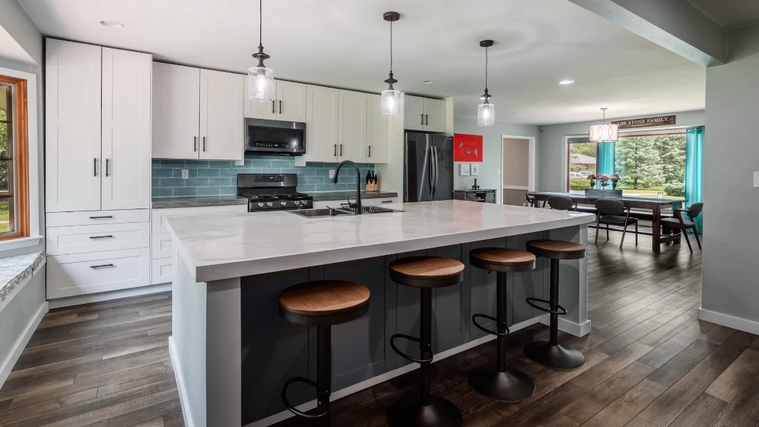Before and after mid-range kitchen renovation featuring new quartz countertops, cabinet replacement, updated flooring, and modern lighting